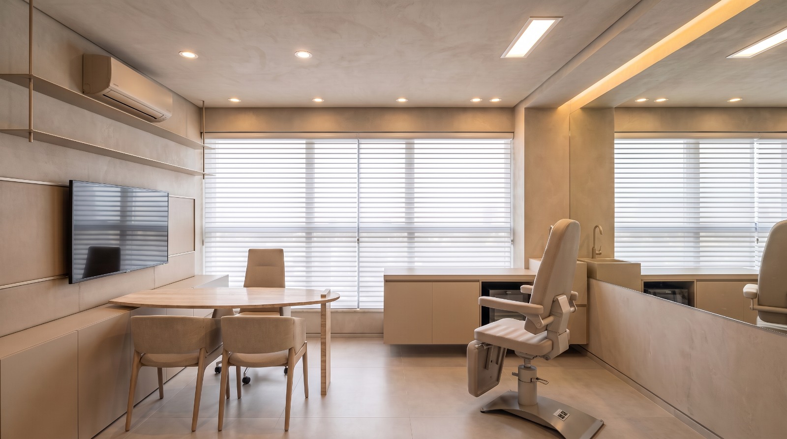 Sala de procedimentos com cadeira clínica reclinável, bancada em pedra e iluminação quente